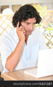 Man sat with laptop and telephone on terrace