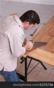 Man sawing plank of parquet