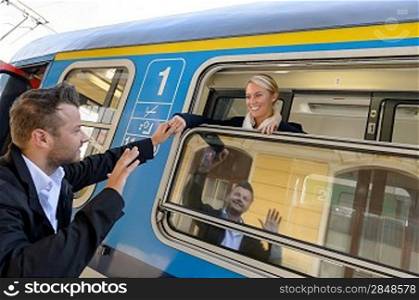 Man saying goodbye to woman on train smiling window commuter
