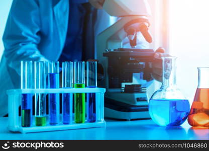 Man scientist working in pharmaceutical laboratory and examining biochemistry sample in microscope. Science technology medicine research and development study concept.