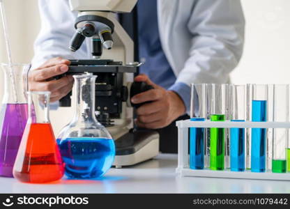 Man scientist working in pharmaceutical laboratory and examining biochemistry sample in microscope. Science technology medicine research and development study concept.