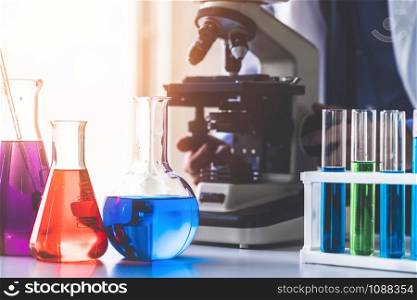 Man scientist working in pharmaceutical laboratory and examining biochemistry sample in microscope. Science technology medicine research and development study concept.