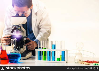 Man scientist working in pharmaceutical laboratory and examining biochemistry sample in microscope. Science technology medicine research and development study concept.