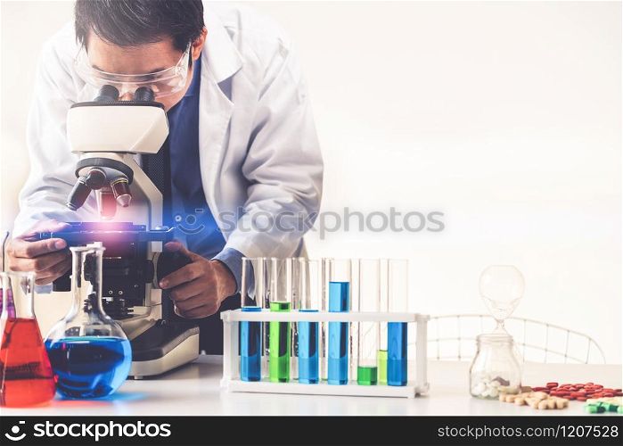 Man scientist working in pharmaceutical laboratory and examining biochemistry sample in microscope. Science technology medicine research and development study concept.. Scientist working in pharmaceutical laboratory.