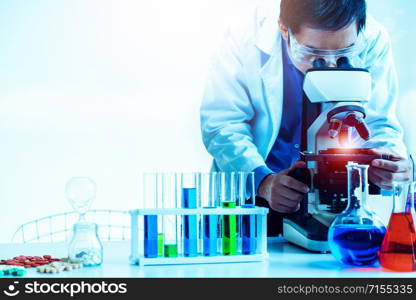 Man scientist working in pharmaceutical laboratory and examining biochemistry sample in microscope. Science technology medicine research and development study concept.