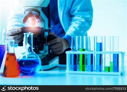 Man scientist working in pharmaceutical laboratory and examining biochemistry sample in microscope. Science technology medicine research and development study concept.