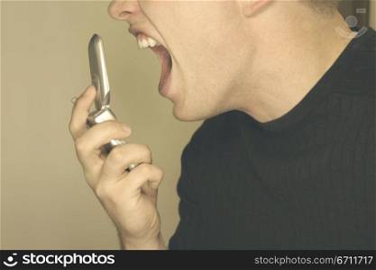Man screaming at cell phone in black sweater and brown background
