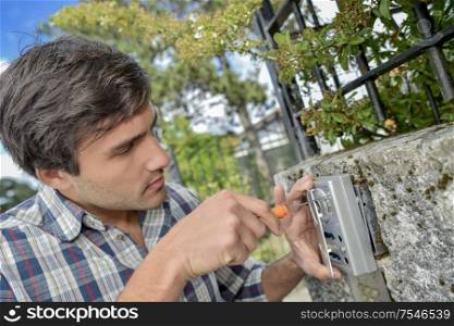 Man screwing security device to exterior wall