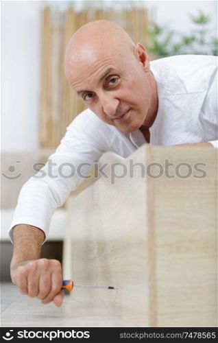 man screws a wood furniture