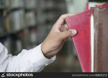 man searching book from textbook shelf in aisle in library