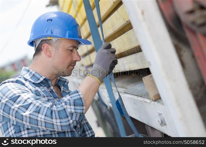 Man securing straps to side of lorry