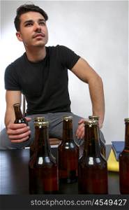 man seeing tv. a young man with black relaxing watching tv with a beer