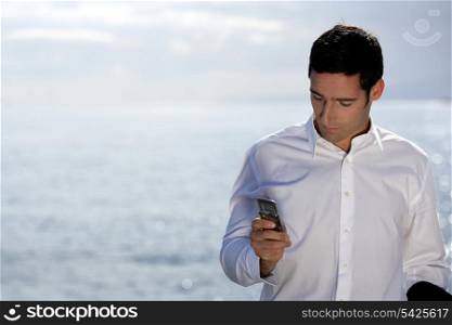 Man sending an SMS by the water&rsquo;s edge