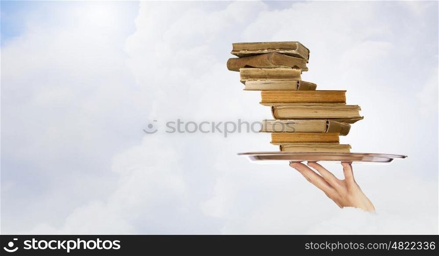 Man serve books. Hand holding tray with pile of old books
