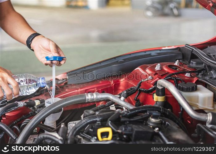 Man service mechanic maintenance inspection service maintenance car Check engine with fill water add water to the wiper car in garage showroom dealership blurred background For automotive automobile