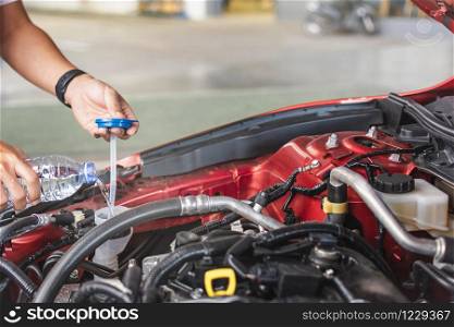 Man service mechanic maintenance inspection service maintenance car Check engine with fill water add water to the wiper car in garage showroom dealership blurred background For automotive automobile