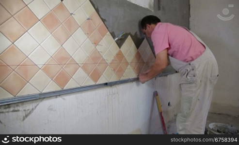 Man setting tile on cement board, Side View, Wide Angle