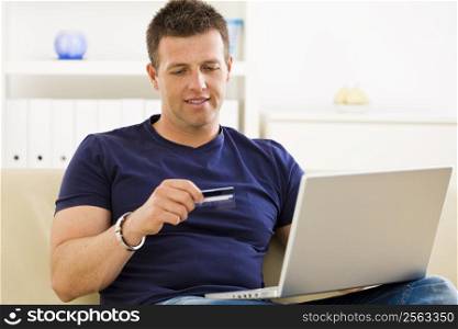 Man shopping online from home using credit card and laptop.