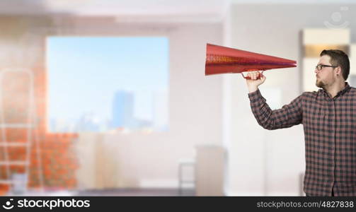 Man shouting in pape cone. Guy in shirt andf glasses make announcement in trumpet