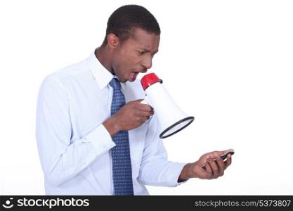 Man shouting through a megaphone at a cellphone