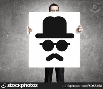 Man show banner with emoticon. Businessman holding and hiding behind card with smiley face emoticon