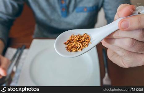 Man showing a spoonful of worms ready to eat. Man showing a spoonful of worms