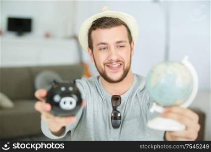 man showing a world-globe and a piggy bank