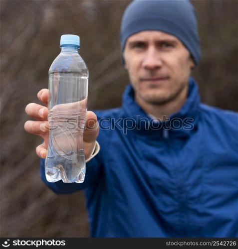 man showing bottle water nature