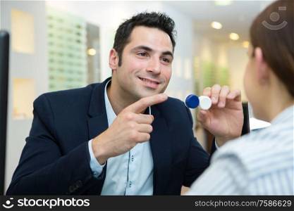 man showing contact lens to female customer