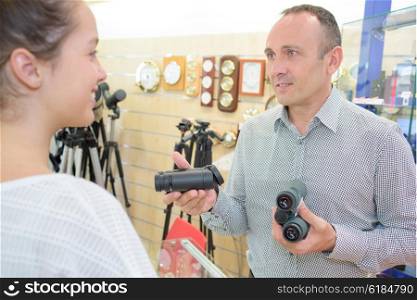 Man showing customer two pairs of binoculars