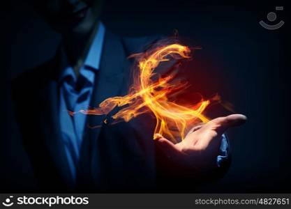 Man showing dollar symbol. Burning euro sign in businessman palm on dark background