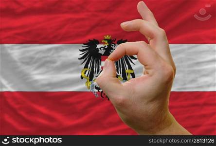 man showing excellence or ok gesture in front of complete wavy austria national flag of symbolizing best quality, positivity and succes
