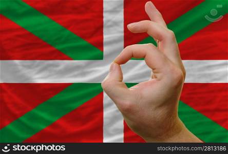 man showing excellence or ok gesture in front of complete wavy basque national flag of symbolizing best quality, positivity and succes