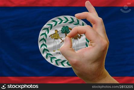 man showing excellence or ok gesture in front of complete wavy belize national flag of symbolizing best quality, positivity and succes