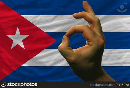 man showing excellence or ok gesture in front of complete wavy cuba national flag of symbolizing best quality, positivity and succes