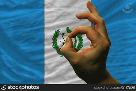 man showing excellence or ok gesture in front of complete wavy guatemala national flag of symbolizing best quality, positivity and succes
