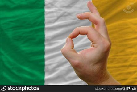 man showing excellence or ok gesture in front of complete wavy ireland national flag of symbolizing best quality, positivity and succes