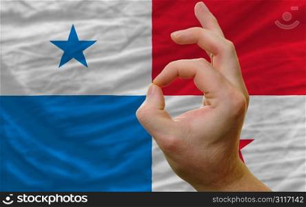 man showing excellence or ok gesture in front of complete wavy panama national flag of symbolizing best quality, positivity and succes
