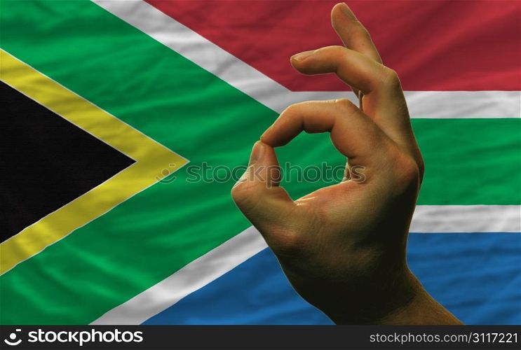 man showing excellence or ok gesture in front of complete wavy south africa national flag symbolizing best quality, positivity and succes