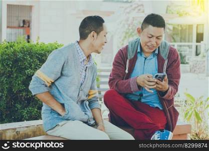 man showing his cell phone to another guy, two guys checking their cell phones, Two young men comparing their cell phones