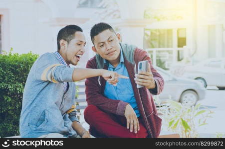man showing his cell phone to another man, two friends checking their cell phones, two young friends having a good time