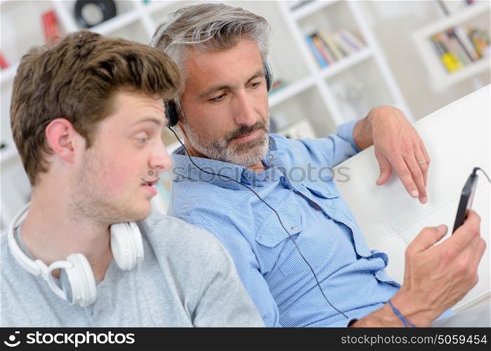 Man showing mp3 screen to son who looks uninterested