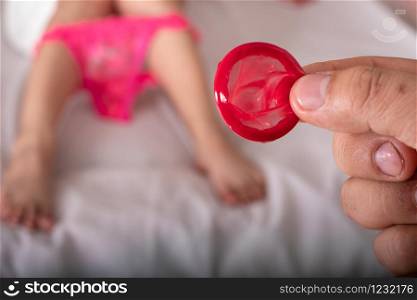 Man showing red condom at the beautiful woman with towel lies in bed, Safe sex and health care and medical, Valentine day concept