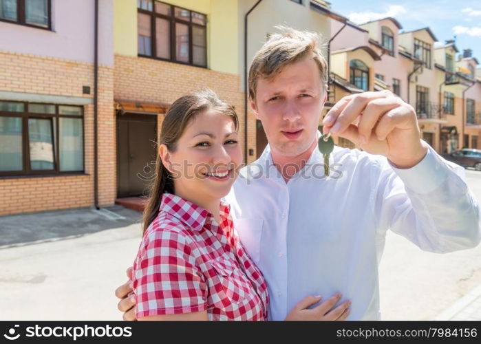 man showing the key of the house and embracing his wife