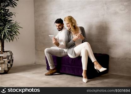 Man showing to young woman information on digital tablet while she holding smartphone