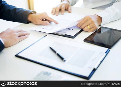 Man signing a car insurance policy, the agent is holding the document