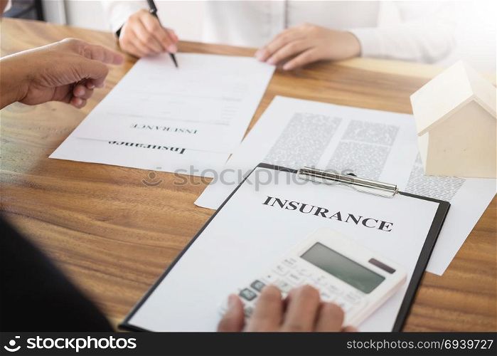 Man signing a car insurance policy, the agent is holding the document