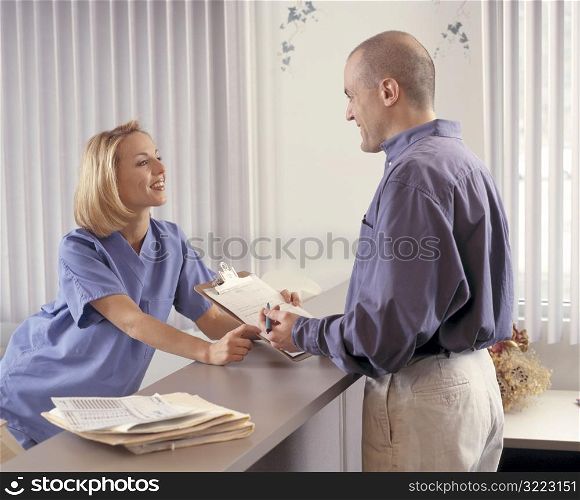 Man Signing in At Hospital Front Desk