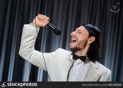 Man singing in front of curtain in karaoke concept