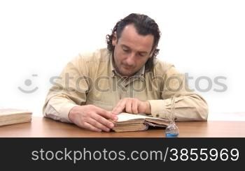 man sits at table and reads old book.